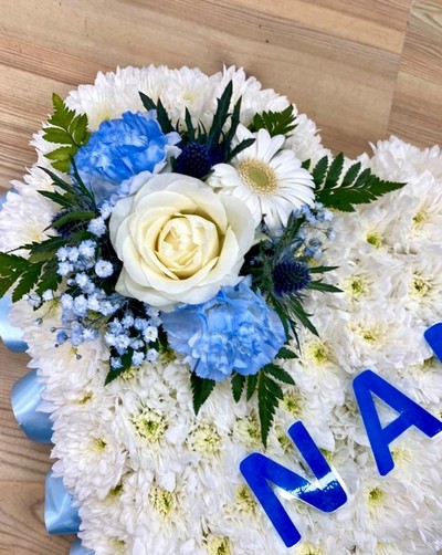 Heart-shaped funeral tribute with laminated wording, white chrysanthemums, delicate ribbon edge, and matching focal. Customisable colour options available.
