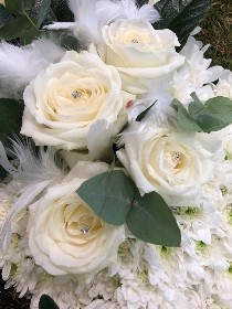 Dove-shaped funeral tribute made with white chrysanthemum on a moss base, featuring a white rose focal, feather and diamanté details, measuring approximately 36 inches high by 24 inches wide.